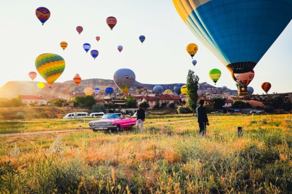 Photo by Emrah Yazıcıoğlu : https://www.pexels.com/photo/people-standing-on-green-grass-field-with-hot-air-balloons-13006331/